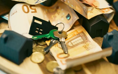Euro currency with house keys and miniature models, symbolizing real estate investment.