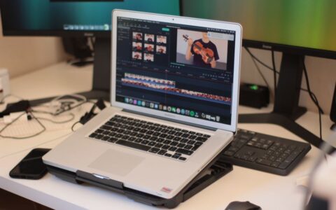 A workspace featuring a laptop editing a video, showcasing modern technology and video editing software.