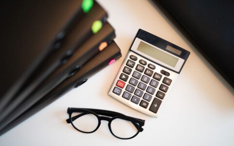 Calculator with glasses and folders on an office desk. Perfect for finance and accounting themes.